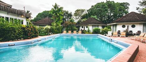A swimming pool with lounge chairs and a tiled deck.