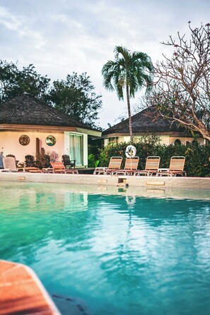 A pool area with lounge chairs and a palm tree. - Kariwak Village Holistic Haven (Crown Point)