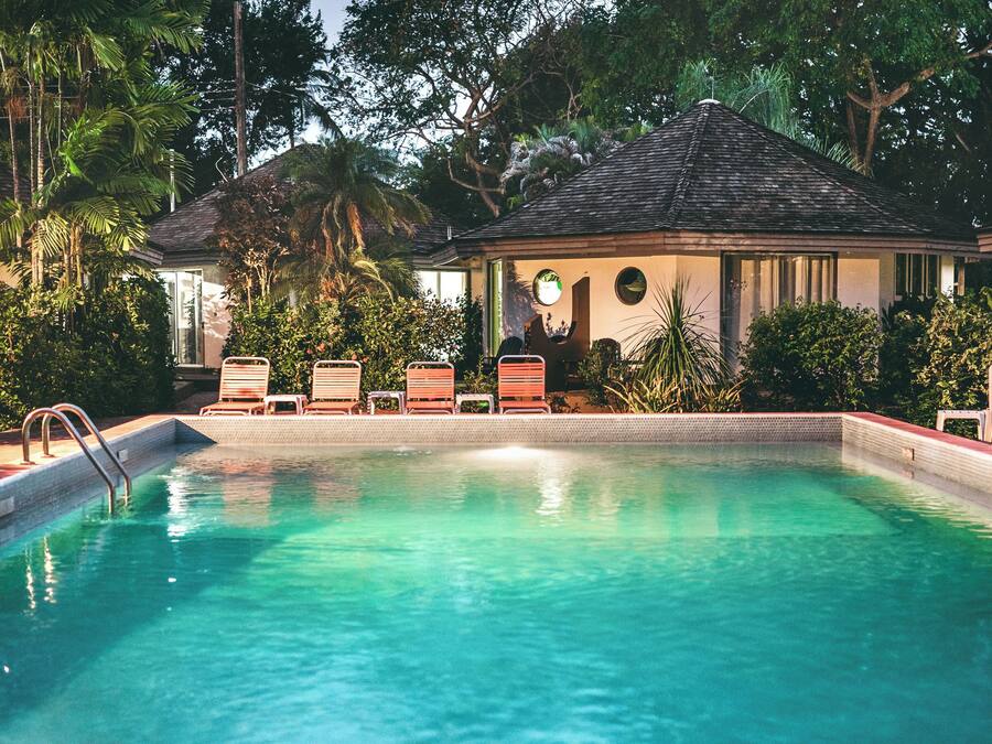 A swimming pool with lounge chairs and a small building with a thatched roof.