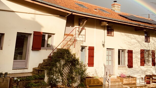 Een huis met een pannendak, schoorsteen en een rode deur.