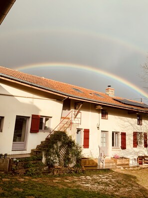 Une maison avec un toit en tuiles, une cheminée et une porte rouge.