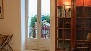 Een woonkamer met een grote houten boekenkast, een kamerkleed met dessin en twee fauteuils.