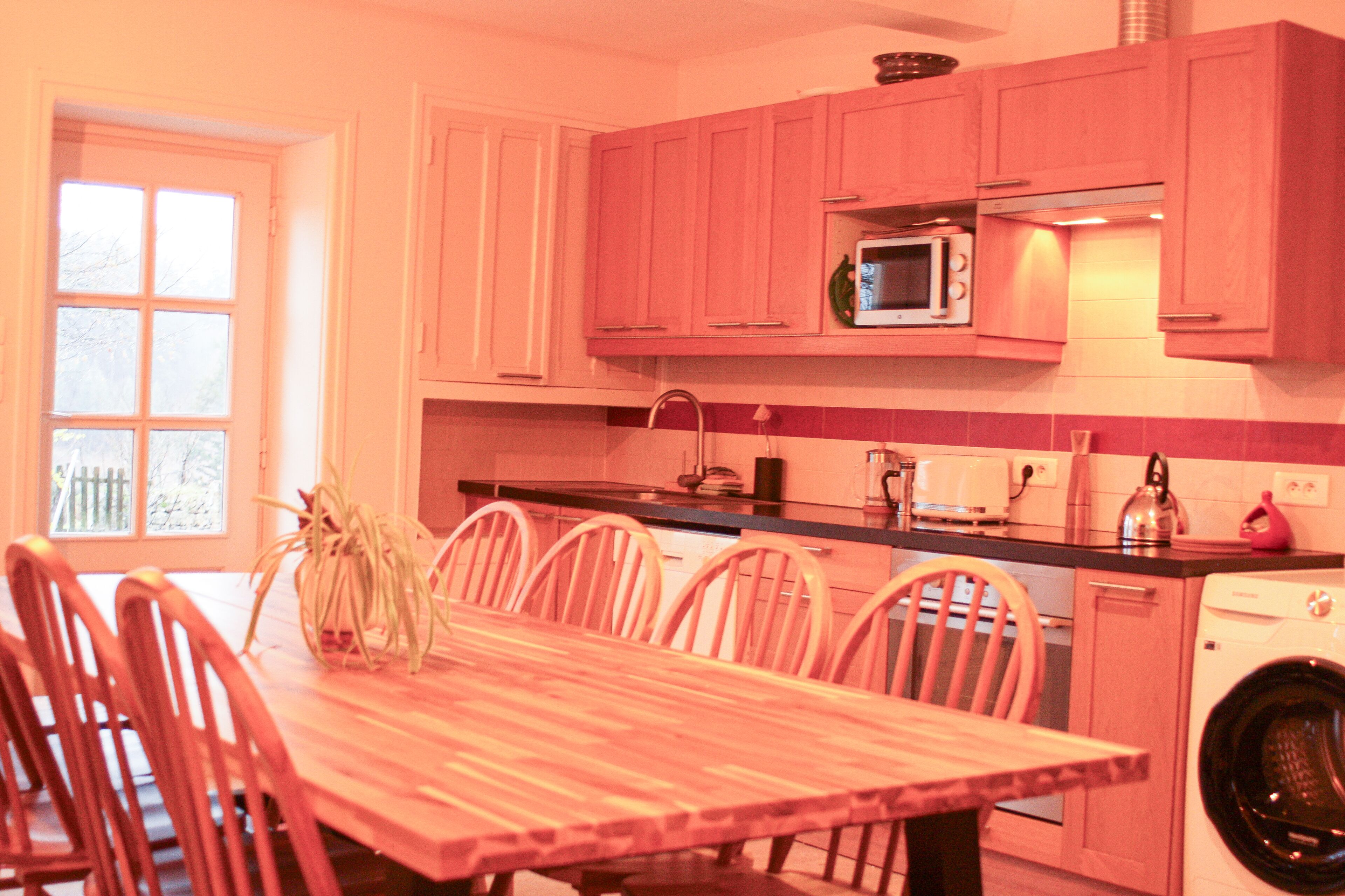 Una cocina con armarios rosados, una mesa de comedor de madera y sillas.