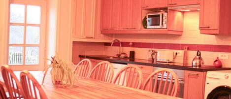 Una cocina con armarios rosados, una mesa de comedor de madera y sillas.