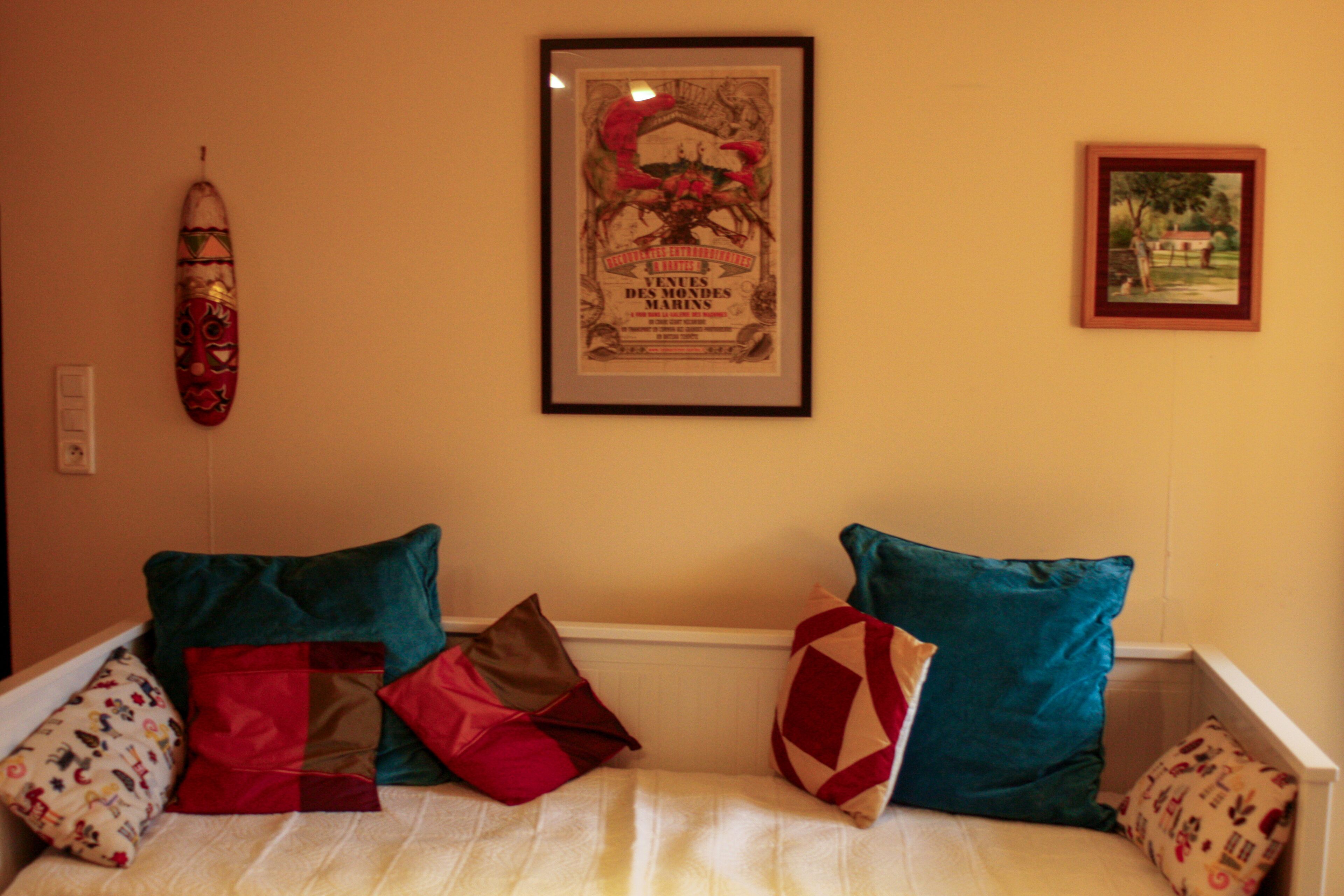 Une pièce avec un lit, des oreillers, une planche de surf et deux tableaux encadrés accrochés au mur.