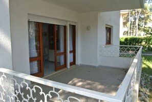 A balcony with a white railing, a door with glass panels, and a small window.