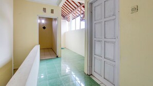 Un pasillo con piso de baldosas verdes, una puerta blanca y un techo a rayas rojas y blancas.