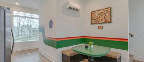 A modern kitchen with a built-in refrigerator, a dining table with benches, and a colorful accent wall.