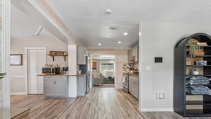A modern kitchen with a central island, built-in appliances, and a view into the dining area. - Modern Pool Home, Central to Beach and Downtown (Seminole)