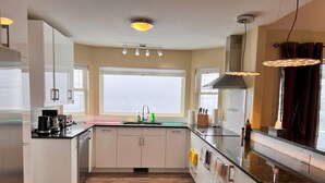 Une cuisine moderne avec des meubles blancs, un plan de travail noir et une fenêtre qui laisse entrer la lumière naturelle.