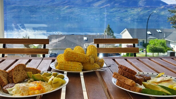 Une table garnie de divers aliments pour le petit-déjeuner, notamment des épis de maïs, des toasts, des œufs et des avocats.