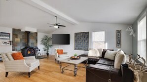 A modern living room with a fireplace, striped sofa, leather couch, and a coffee table. - Pocono Mountains, Hidden-Gem GameRoom, Firepit, Min to all Attractions (Cresco)