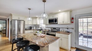 A modern kitchen with white cabinets, stainless steel appliances, a marble island, and pendant lighting. - Pocono Mountains, Hidden-Gem GameRoom, Firepit, Min to all Attractions (Cresco)