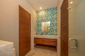 A bathroom with a wooden vanity, a mirror, and a geometric patterned wall. - 3BD Begati Ocean View Pool Beach Resort (San José del Cabo)
