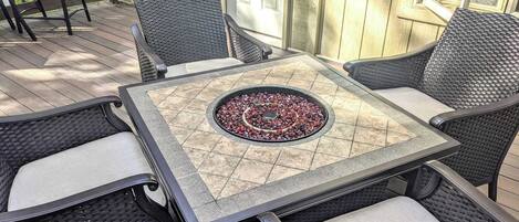 A patio with a table and chairs, a fire pit, and a wooden deck.