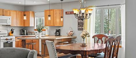 A modern kitchen with wooden cabinets, a central island, and a dining area with a wooden table and chairs.