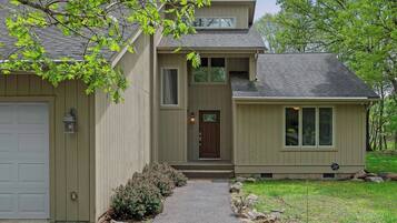 A two-story house with a front door, a garage, and a small attached structure.