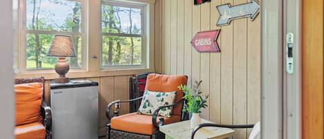 Interior acogedor de una cabaña con una silla de mimbre, una mesita y un cartel que dice 'Lake Cabins'.