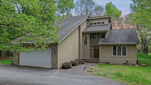 A two-story house with a garage, a front porch, and a small attached shed.