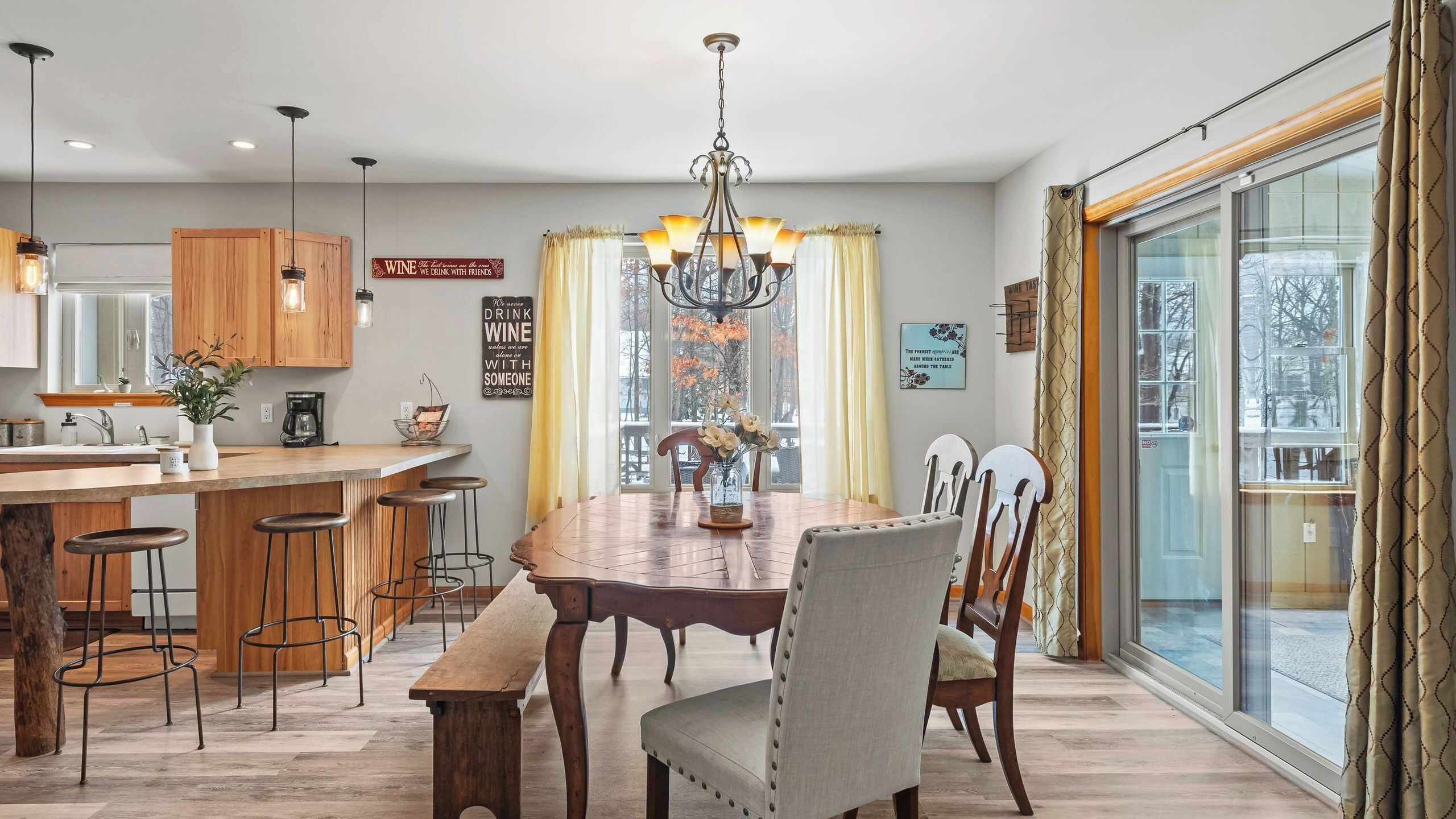 A dining area with a wooden table, bar stools, and a chandelier.
