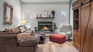 Un salon chaleureux avec une cheminée, un canapé, un fauteuil et un meuble en bois.