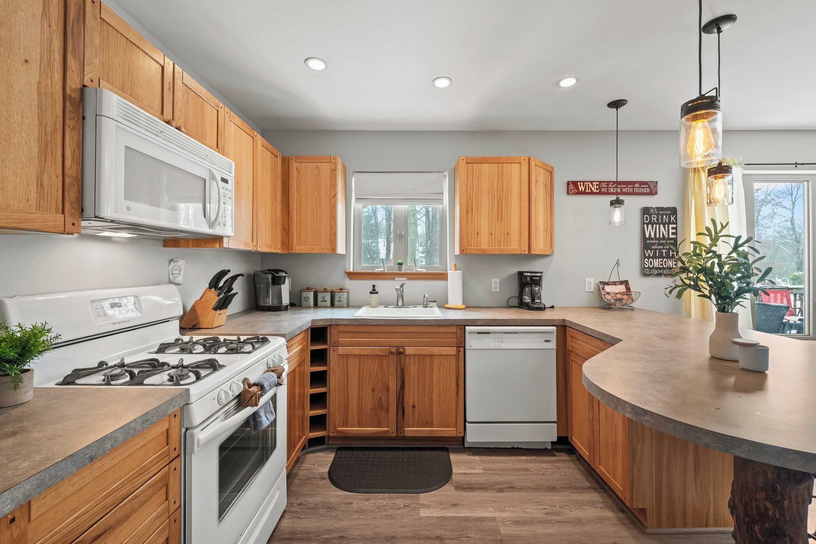 Una cocina moderna con armarios de madera, microondas, estufa y lavavajillas.
