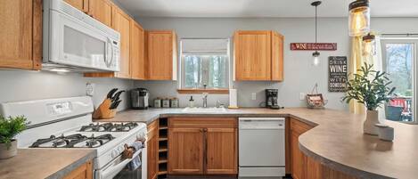 Una cocina moderna con armarios de madera, microondas, estufa y lavavajillas.