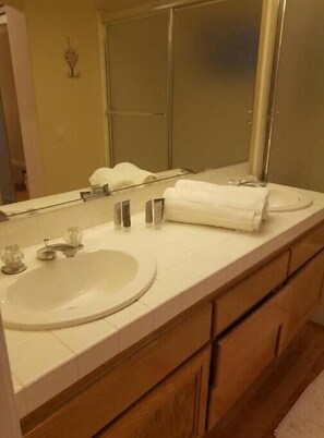 A bathroom with a large mirror, two sinks, and wooden cabinets.