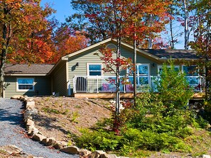 A two-story house with a front porch, a small deck, and a driveway leading to the house.