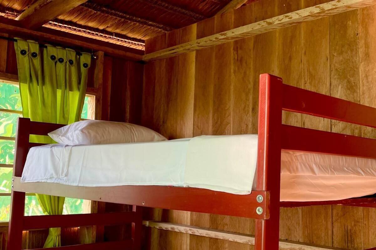 A bunk bed with white bedding in a wooden room with a thatched roof.
