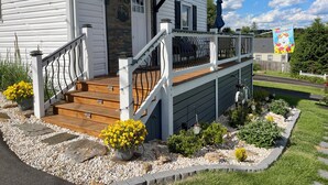 Une maison avec une terrasse en bois, un porche et une banderole de bienvenue.