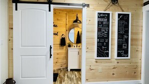 Un intérieur en bois avec une porte blanche, un miroir et deux tableaux noirs sur lesquels est écrit du texte.