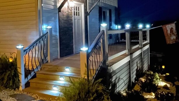 Une maison avec un porche, des marches et un éclairage extérieur.
