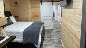 Une pièce en bois avec un lit, un bureau et un téléviseur fixé au mur.