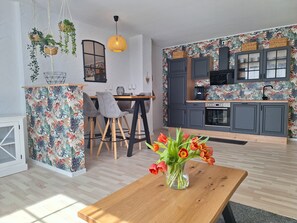Une cuisine moderne avec des meubles gris, un plan de travail en bois et une hotte noire.