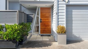 A modern house with a wooden door, a garage door, and a number '2' on the wall. - Fresh on Fletcher - Taupo Holiday Home (Taupo)