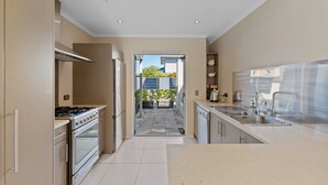 A modern kitchen with stainless steel appliances, a central island, and a view to a garden. - Fresh on Fletcher - Taupo Holiday Home (Taupo)