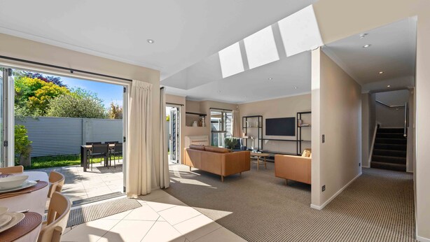 A spacious living area with a sofa, a TV, and a dining area with a table and chairs. - Fresh on Fletcher - Taupo Holiday Home (Taupo)