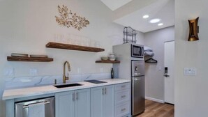 A modern kitchen with light blue cabinets, a stainless steel refrigerator, and a microwave.