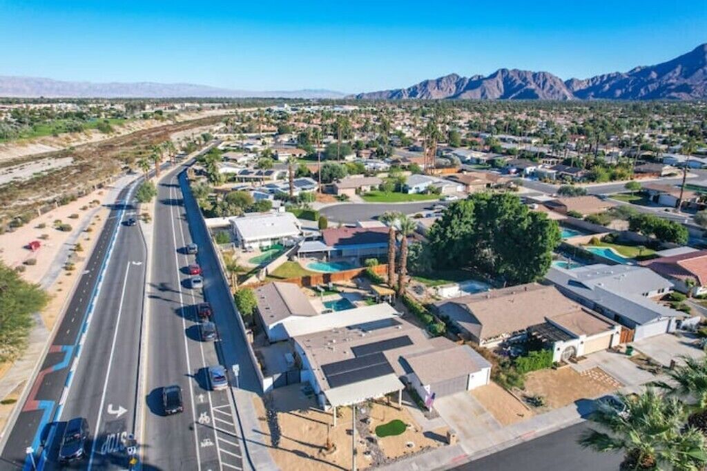 A residential area with houses, a road, and mountains in the background.