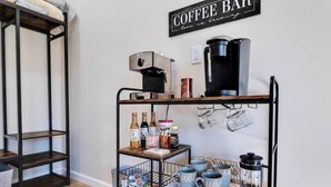 A coffee bar setup with a coffee machine, mugs, and various coffee-related items on shelves.