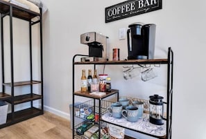 Un espace café aménagé avec une machine à café, des tasses et divers accessoires liés au café, disposés sur des étagères.
