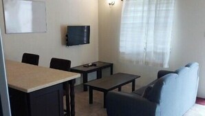 A small living room with a sofa, a table, and a TV.