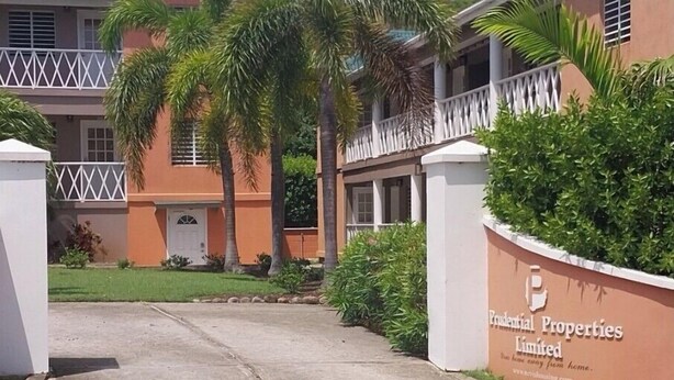 A building with a gated entrance, palm trees, and a sign for Providential Properties Limited.