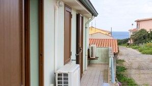 A narrow pathway leading to a building with a tiled roof and a view of the sea.