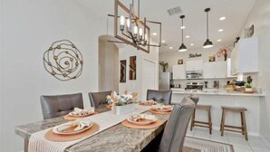 Un espace repas moderne avec une table en marbre, des chaises en cuir et une cuisine en arrière-plan.