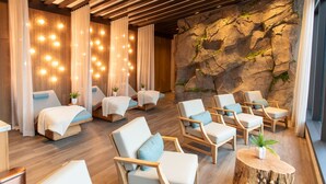 Un cuarto de spa con sillones de masaje, piso de madera y una pared de rocas.