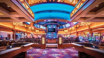 A casino interior with slot machines, a bar area, and a large digital display.