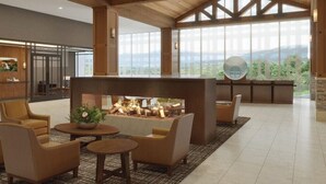 Amplia sala de estar con chimenea, asientos cómodos y grandes ventanas con vistas al exterior.