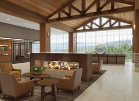 A spacious living area with a fireplace, comfortable seating, and large windows offering a view of the outdoors.